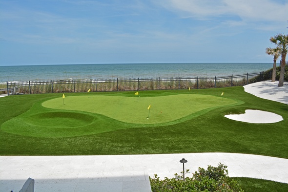 Phoenix Synthetic grass golf green by the sea with yellow flags and a sand bunker